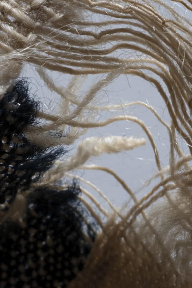 A close view of an antique woven textile with its threads frayed and pulling loose